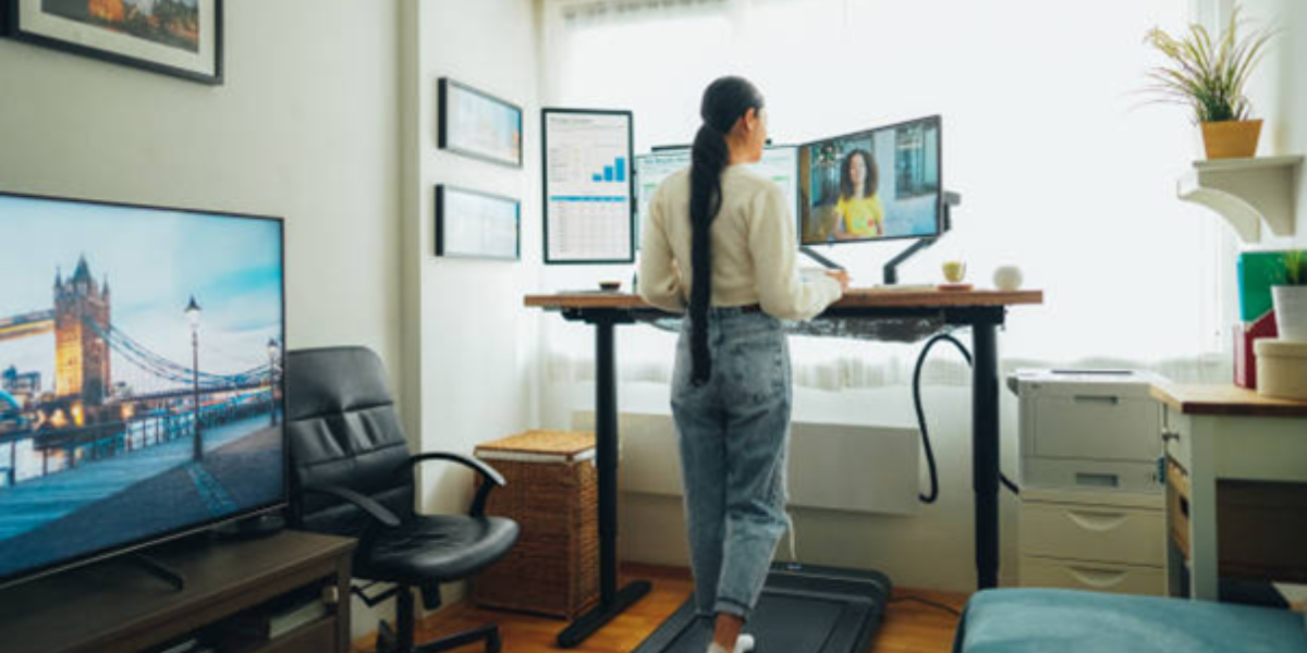 Remote Work Wellness Tips: Creating a Healthy Work-Life Balance When Working from Home A woman stands on a treadmill, typing on a laptop while exercising.