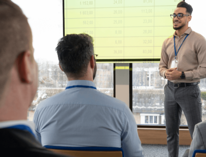 A man presenting to an audience, engaging with the group while using visual aids.