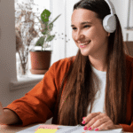 IELTS in the Digital Age: Is Online Training Better Than In-Person Classes? A woman wearing headphones sits at a desk, focused on her laptop while working or studying.