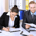 Top 10 Contract Management Skills Every Professional Must Learn A group of business professionals seated at a table, reviewing documents and discussing strategies.