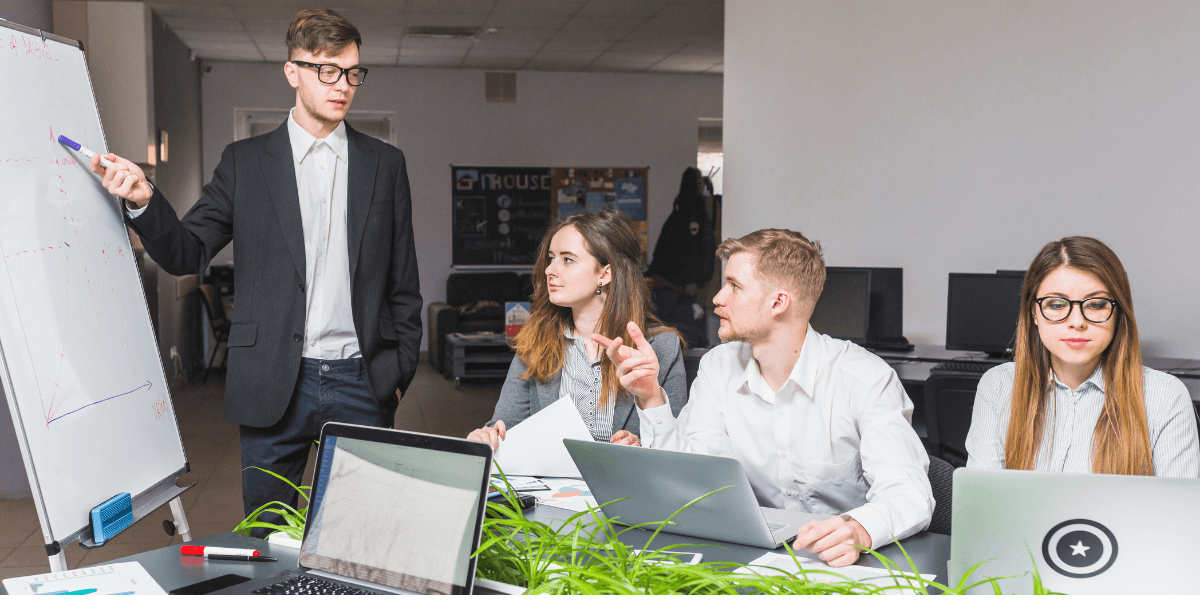 A diverse group of professionals working collaboratively at laptops in a modern office setting.